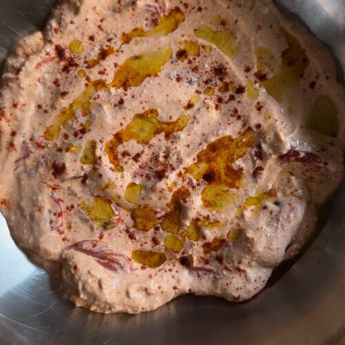 Cheesy dip with olive oil and paprika in a stainless steel bowl