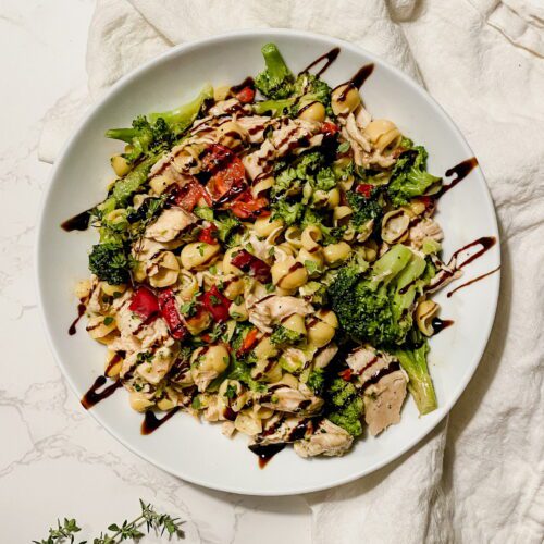 Pasta shells with cheese topped with tomatoes, broccoli, and chicken