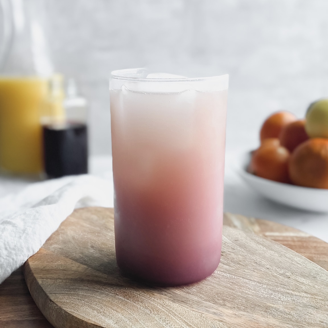 An orangey-pink sunrise mocktail drink made with pomegranate juice, orange juice, and coconut water 