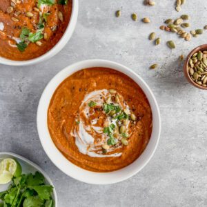 Red lentil thai soup with onion and coconut milk in a white ceramic bowl