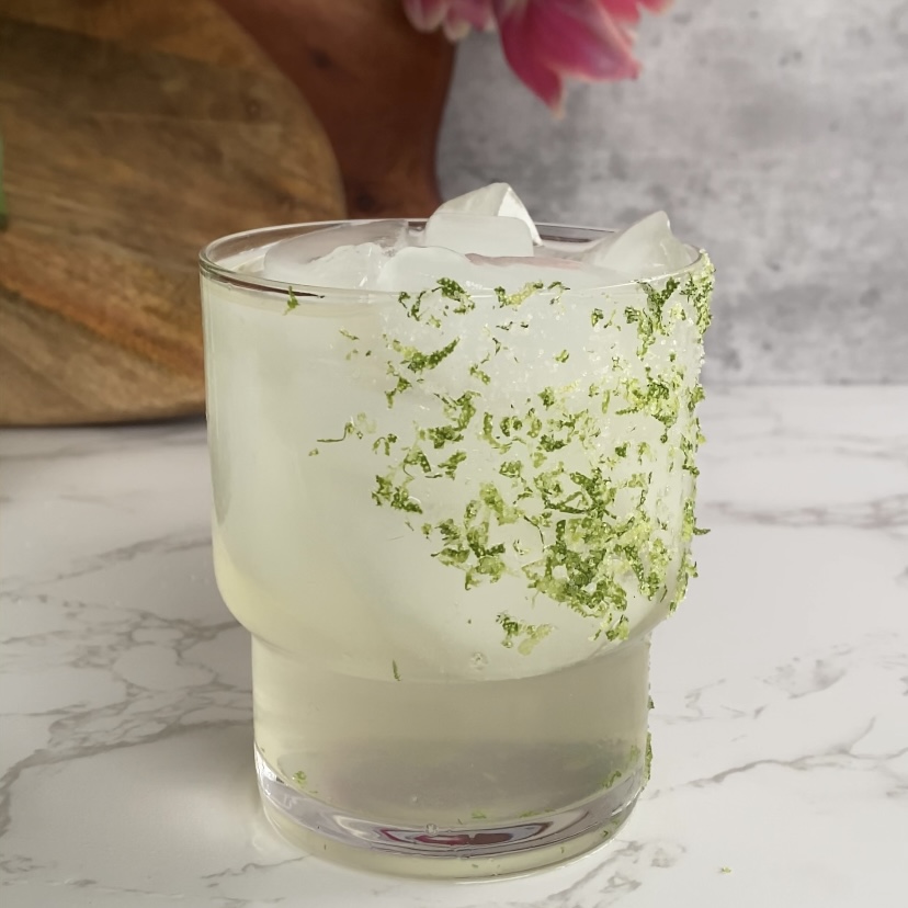 A clear mineral drink served in a glass with a lime and salt rim