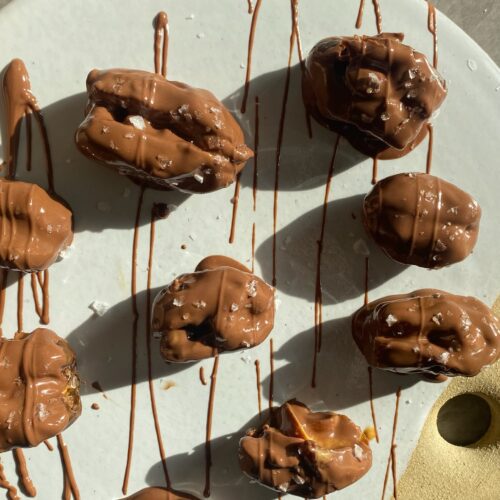 Chocolate peanut butter stuffed dates topped with flaky salt on a plate