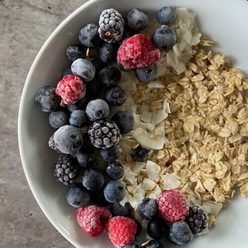 Oatmeal in a bowl with berries and coconut flakes in a glass bowl