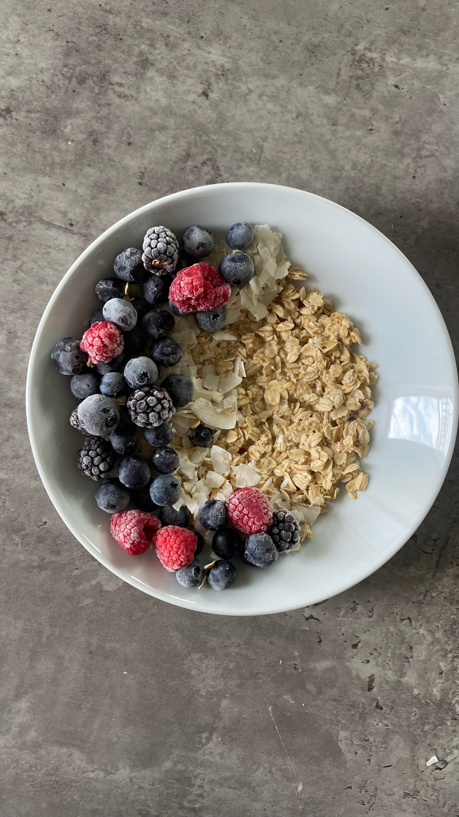 Oatmeal in a bowl with berries and coconut flakes in a glass bowl